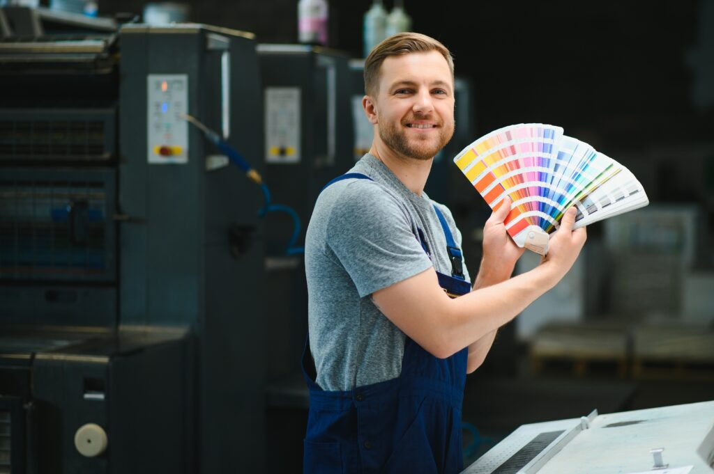 man working in printing house with paper and paints