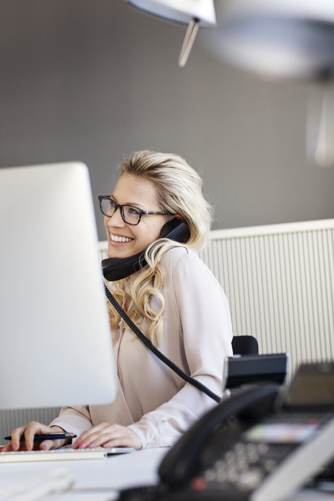 smiling blond woman in office on the phone