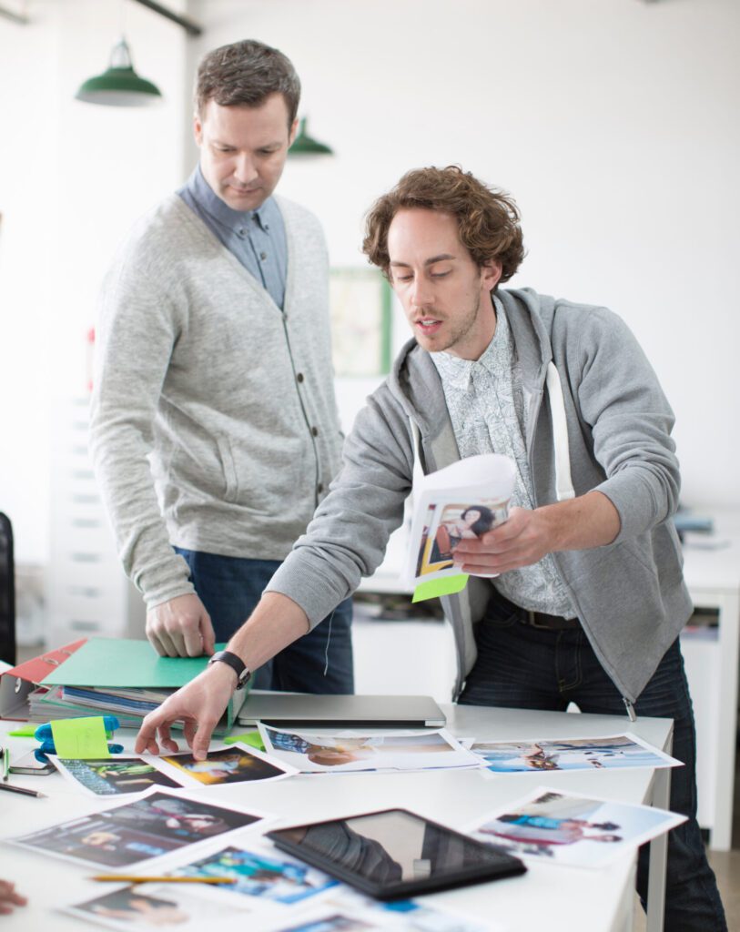 young man showing plans to colleagues on meeting in creative office